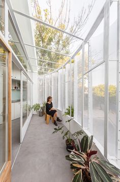 a woman standing on the side of a building next to plants