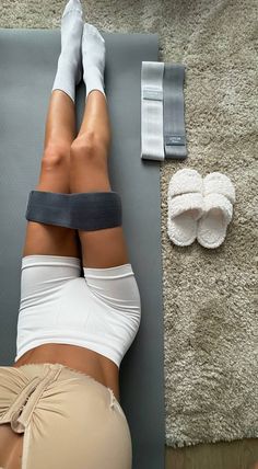 a woman laying on a yoga mat with her legs crossed