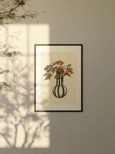 a vase with orange flowers in it is hanging on the wall next to a plant