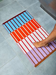 a person is standing on the floor with their foot on an area rug that looks like stripes