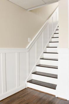 an empty room with stairs and hard wood flooring on the bottom part of the wall