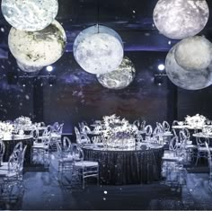 the tables are set up for an event with moon lights hanging from the ceiling above them