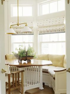 a kitchen with a table, bench and window in the corner next to a potted plant