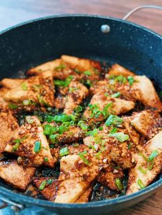 tofu in a skillet with green onions and seasoning