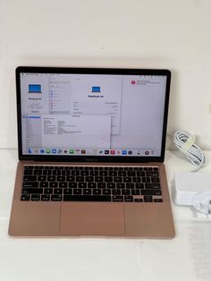 an open laptop computer sitting on top of a white table next to a charger