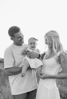 a man and woman holding a baby in a field