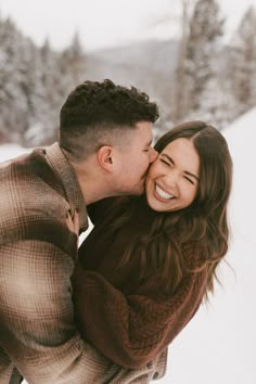 a man and woman are kissing in the snow