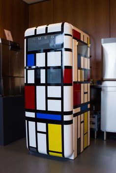 a refrigerator covered in multicolored squares sitting on top of a kitchen counter next to a refrigerator freezer