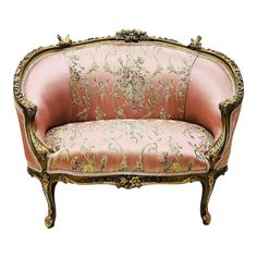 an ornately decorated pink couch with gold trimmings on the arms and back