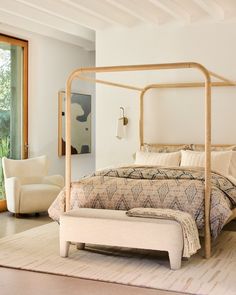 a bedroom with a bed, chair and ottoman next to a sliding glass door that leads outside