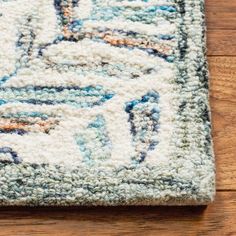 an area rug is laying on the floor with wood in the background and a wooden floor