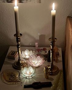 two candles are sitting on a table with other items around it and one candle is lit