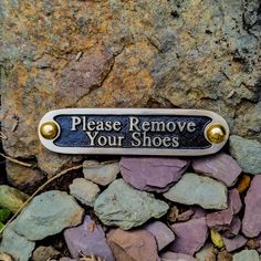 there is a plaque that says please remove your shoes on the ground next to some rocks