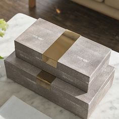 two gray boxes sitting on top of a marble table