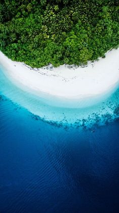 an island in the middle of water surrounded by green trees and sand, as seen from above