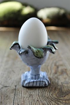 an egg is sitting in a silver vase