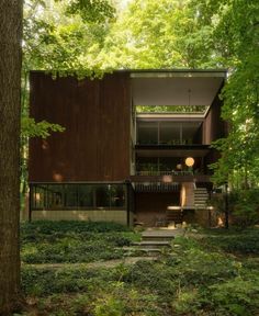 a house in the woods with stairs leading up to it's second story and trees surrounding