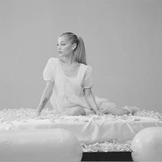 a woman sitting on top of a bed covered in white sheets