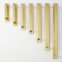 five brass handles are lined up on a white surface and one is in the shape of rectangles