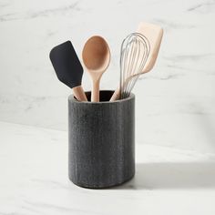 wooden utensils in a black cup on a marble counter