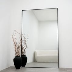 a mirror sitting on top of a wooden table next to a vase with branches in it