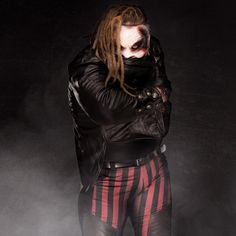 a man with dreadlocks is dressed in black leather and red striped tights