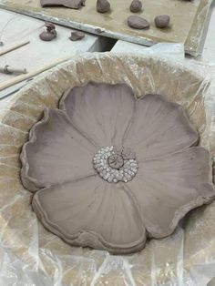 a large flower shaped bowl sitting on top of a table covered in plastic wrappers