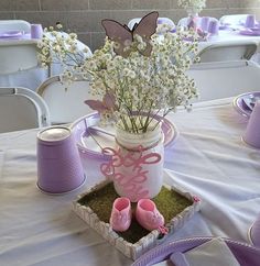 a table set with purple and white flowers in a vase, baby's breath booties