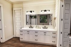 a large bathroom with double sinks and two doors leading to the other side of the room