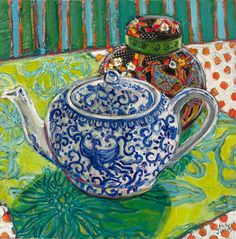 two teapots sitting on top of a green and blue table cloth next to each other