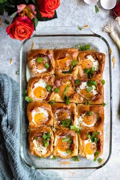 a glass baking dish filled with eggs, ham and green onions next to some flowers