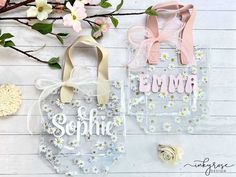 two clear bags with pink and white flowers on them, one has a name tag