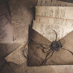 an old envelope is tied with string and sits on top of some papers that have been placed together