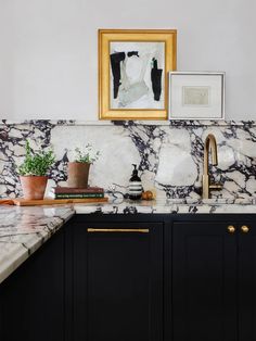 a kitchen with marble counter tops and black cabinets, gold trim on the faucet