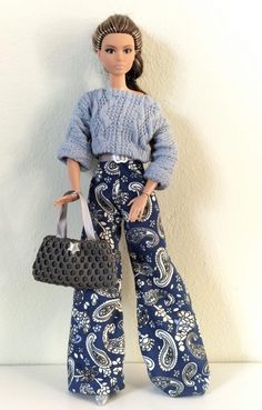 a doll is holding a purse and posing for the camera