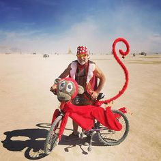 a man riding on the back of a red bike with a monkey attached to it