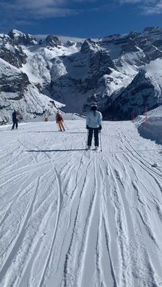 two people on skis standing in the snow with mountains in the backgroud