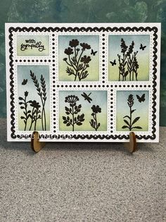 a card with flowers and butterflies on it, sitting on top of a wooden stand