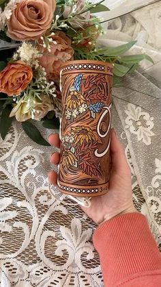 a woman is holding a coffee cup with the letter s on it and flowers in the background