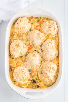 a casserole dish with meatballs and vegetables in it on a white table