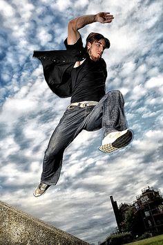 a man flying through the air while riding a skateboard in front of a cloudy sky