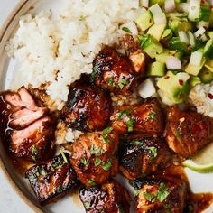 a white plate topped with meat, rice and veggies next to cucumbers