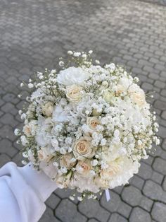 a bridal bouquet is being held on the street by someone holding it in their hand