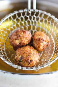 three cooked meatballs in a wire basket