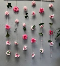 pink flowers are hanging on the wall next to a potted plant