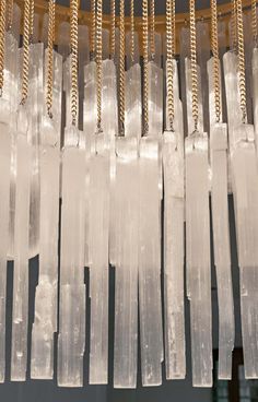 some very pretty clear glass pieces hanging from a chandelier with gold chains on it