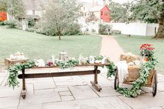 an outdoor table with greenery and candles on it