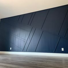 an empty room with dark blue walls and wood floors