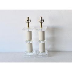 two candle holders with candles in them sitting on a table next to a white wall