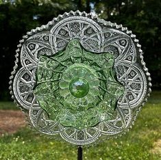 a green glass plate sitting on top of a metal stand in front of some grass